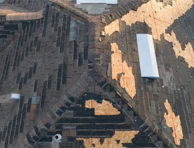 A wind damaged home with its asphalt shingles torn off, requiring storm damage repair in Central Illinois
